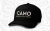 Black Camo Silicone Logo Split-Panel Hat with a white CAMO NATURAL LEAF WRAPS rectangular patch, set on a light camo-patterned background.